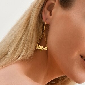 May include: Gold dangle earrings with the name "Alyssa" spelled out in cursive.