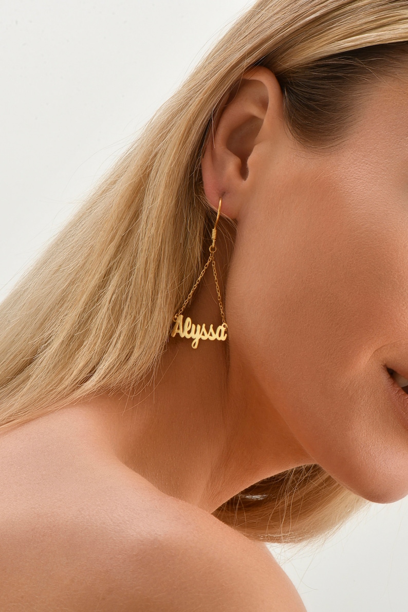May include: Gold dangle earrings with the name "Alyssa" spelled out in cursive.