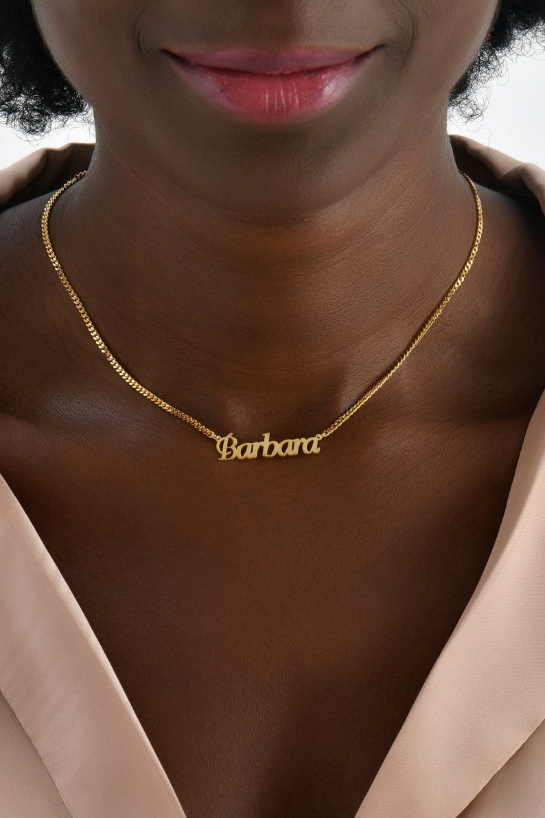 Op de afbeelding: Een gouden ketting met een naamhanger met de tekst "Barbara".
