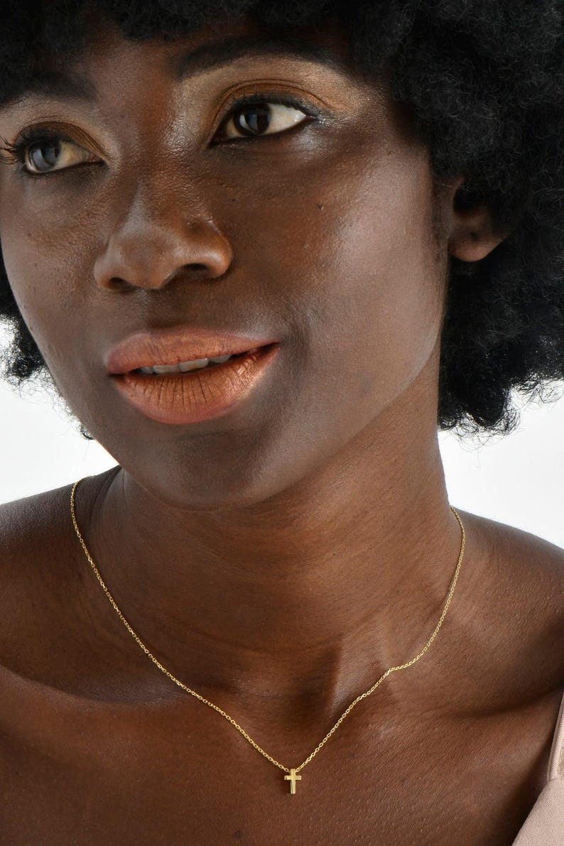 May include: A gold chain necklace with a small gold cross pendant.
