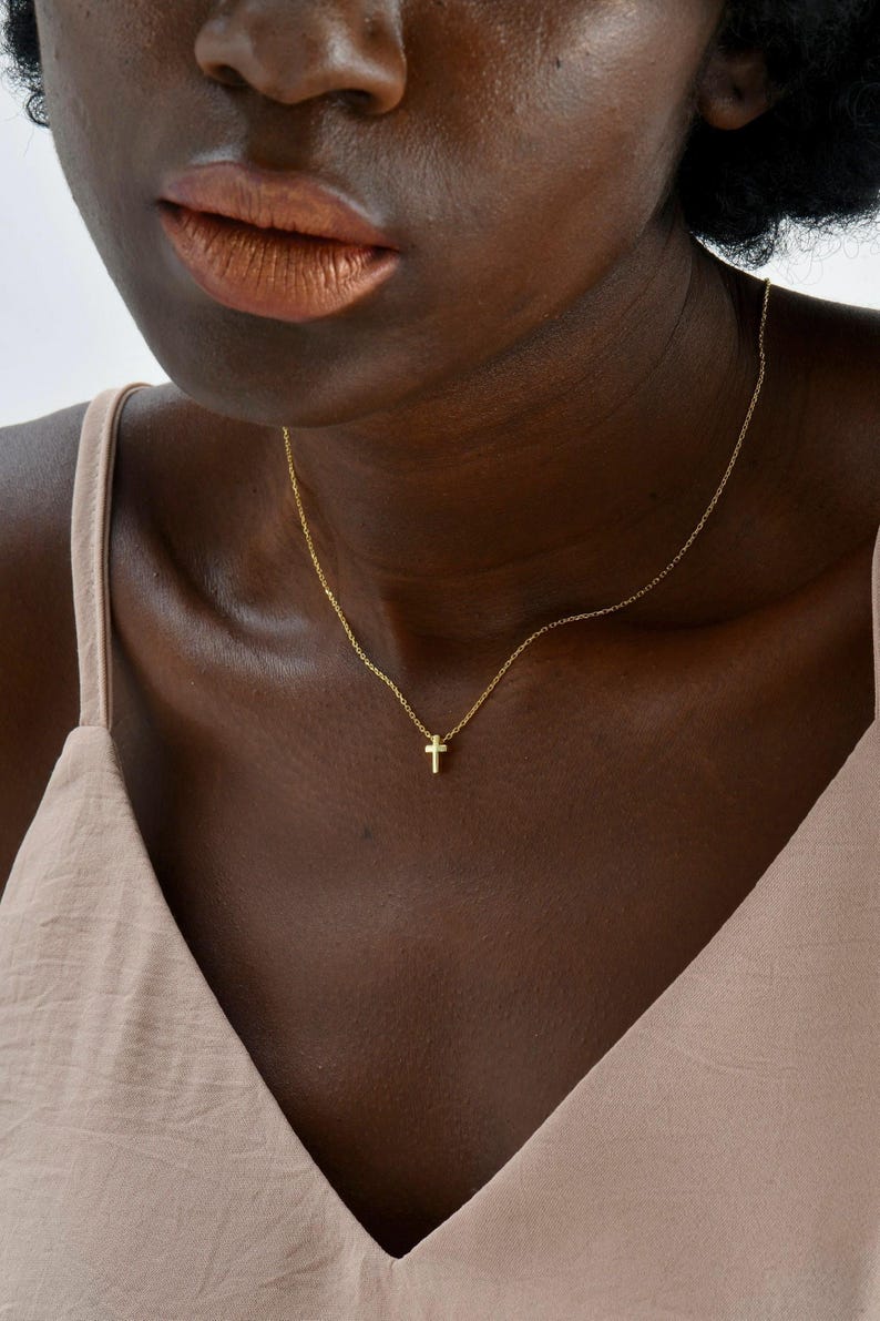 May include: A gold chain necklace with a small gold cross pendant.