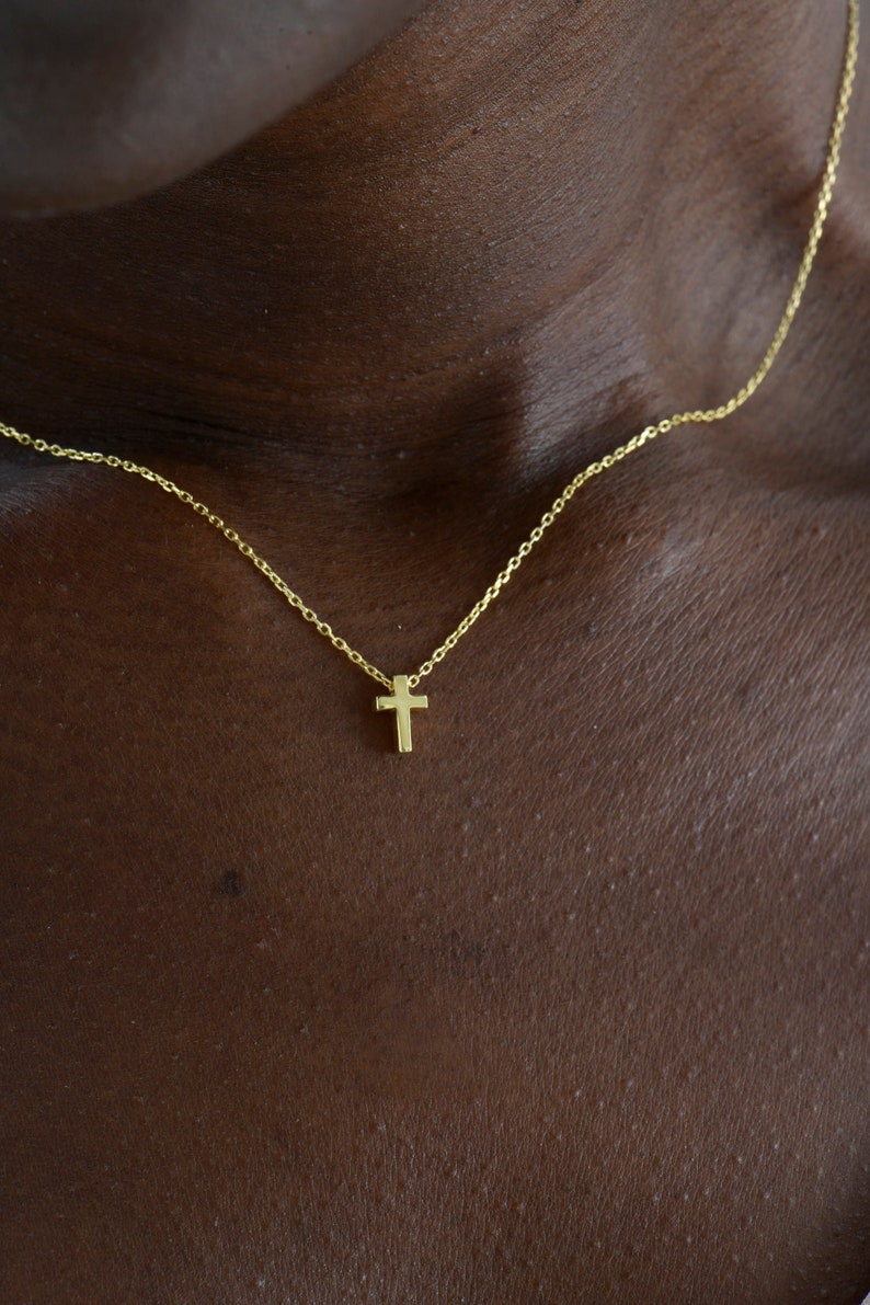 May include: A delicate gold chain necklace with a small, simple cross pendant.