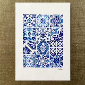 May include: A rectangular white print featuring a grid of twelve distinct blue and white tile patterns. Each square displays a unique geometric or floral motif in varying shades of blue. The word "lisbon" is written in cursive in the bottom right corner.