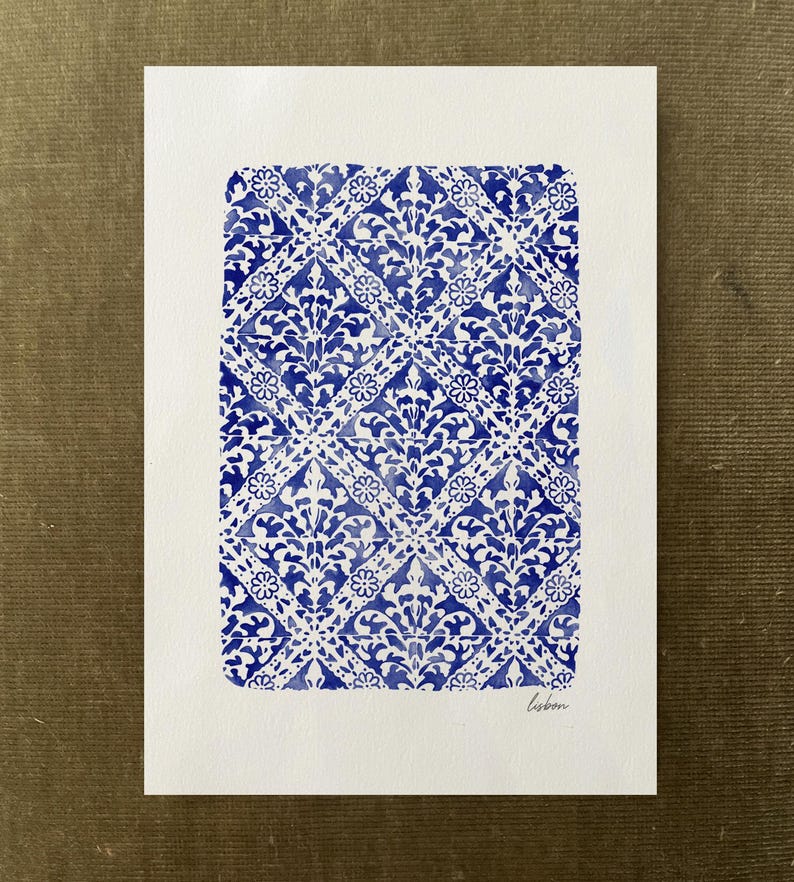 May include: A rectangular white paper print featuring a repeating blue watercolor pattern of diamonds and floral motifs. The design is arranged in a grid, and the word "lisbon" is handwritten in small black cursive letters in the bottom right corner.
