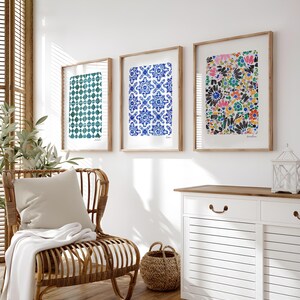 May include: Three framed rectangular wall art prints displayed in a row. The left print features a teal geometric tile pattern. The center print displays a blue and white floral tile design. The right print shows a colorful abstract floral pattern.