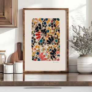 May include: A framed art print with a mosaic design in shades of red, blue, yellow, and black. The word "Barcelona" is written in cursive at the bottom. The print is displayed in a wooden frame. The artwork is suitable for home decor.