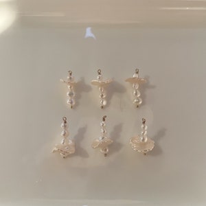 May include: Six pearl and gold pendant charms. Each charm features a cluster of white pearls and a gold-toned, layered, shell-shaped design.