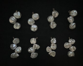May include: Eight white pearl pendants, each with a different arrangement of three or four pearls, hanging from a gold chain.