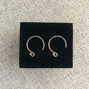 Può includere: Un paio di orecchini a cerchio in oro con un design semplice e minimalista. Gli orecchini sono piccoli e delicati, e sono perfetti per l'uso quotidiano.