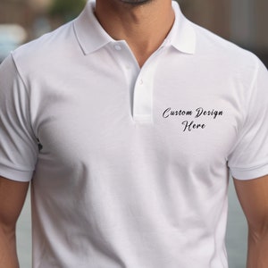 May include: White polo shirt with short sleeves and a button-up collar. The shirt has the text "Custom Design Here" printed on the front.