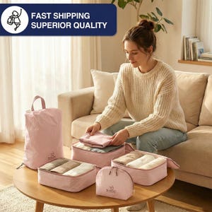 May include: A collection of pink travel organizers and packing cubes on a round wooden table. The organizers are in various sizes and shapes, including a large tote bag, rectangular cubes, and a zippered pouch. The text "FAST SHIPPING SUPERIOR QUALITY" is in a blue banner.