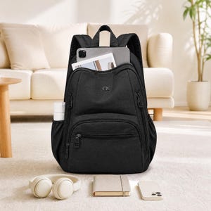 May include: A black backpack with multiple zippered compartments, a top handle, and adjustable shoulder straps. The bag features a small logo on the front, a side pocket holding a white bottle, and a tablet tucked into the main opening.