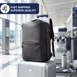 May include: A black backpack with a laptop sleeve, sitting atop a silver rolling suitcase in an airport. The backpack has multiple compartments and adjustable straps. The image includes the text "FAST SHIPPING SUPERIOR QUALITY".