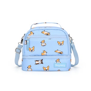 May include: A light blue lunch bag with a double zipper closure and a shoulder strap. The bag features a repeating pattern of cartoon corgis in various poses. The bag has a label that reads "Baystory".