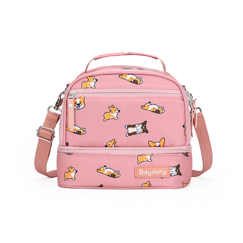 May include: Pink double-decker lunch bag with a zipper closure and adjustable shoulder strap. The bag features a repeating pattern of cartoon corgis in various poses. The bag has a label that reads "Baystory".