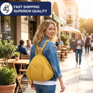 May include: A woman wearing a denim jacket and jeans, carrying a mustard-yellow backpack. The backpack has a front pocket and adjustable straps. The image includes text that says "FAST SHIPPING SUPERIOR QUALITY". The scene is set on a city street with outdoor seating.