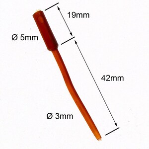Puede incluir: Un dispositivo médico de plástico marrón con un diámetro de 5 mm en la parte superior y 3 mm en la parte inferior. El dispositivo tiene 42 mm de largo y una sección de 19 mm en la parte superior.
