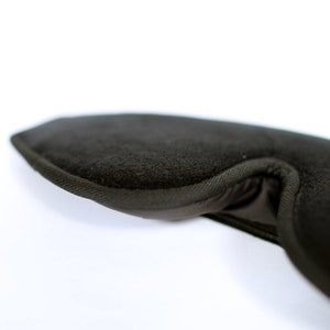 Puede incluir: Primer plano de una m&aacute;scara para dormir marr&oacute;n oscuro. La m&aacute;scara est&aacute; hecha de un material suave y texturizado y tiene una forma curva para adaptarse a los contornos de la cara. Los bordes est&aacute;n cuidadosamente acabados con una tela m&aacute;s oscura.