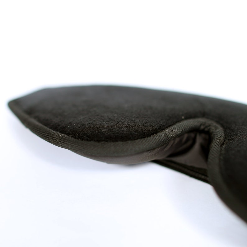 Puede incluir: Primer plano de una m&aacute;scara para dormir marr&oacute;n oscuro. La m&aacute;scara est&aacute; hecha de un material suave y texturizado y tiene una forma curva para adaptarse a los contornos de la cara. Los bordes est&aacute;n cuidadosamente acabados con una tela m&aacute;s oscura.