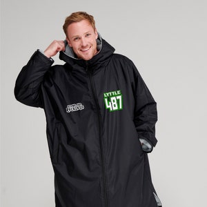 Op de afbeelding: Zwarte jas met capuchon en een ritssluiting over de hele lengte. De jas heeft de tekst "LYTTLE 487" in groen en wit, en de tekst "YOUNG AND RECKLESS" in zwart en wit. De jas heeft een grijze binnenvoering.