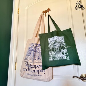 Peut inclure: Deux sacs fourre-tout en toile suspendus &agrave; un crochet en forme de champignon. Un sac est blanc cass&eacute; avec une illustration au trait bleu de la librairie Shakespeare and Company. L'autre sac est vert fonc&eacute; avec un motif blanc repr&eacute;sentant un chat.