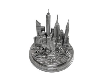 May include: Silver-toned metal model of the New York City skyline, featuring the Statue of Liberty, the Empire State Building, and other iconic landmarks. The model is on a circular base with the words "New York" inscribed on it.
