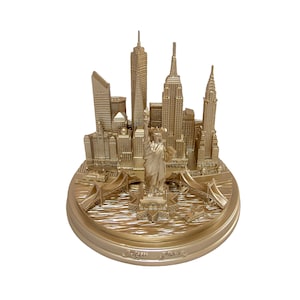 Peut inclure: Une réplique miniature dorée de l'horizon de New York, y compris la Statue de la Liberté, sur une base circulaire.