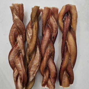 May include: Four braided dog chews made of natural bully sticks. The chews are brown and have a slightly reddish hue.
