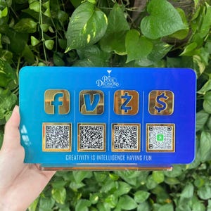May include: A rectangular blue and teal gradient acrylic sign featuring the white text Pour Decisions and the quote Creativity is intelligence having fun. It displays four gold social media icons above four corresponding QR code squares.