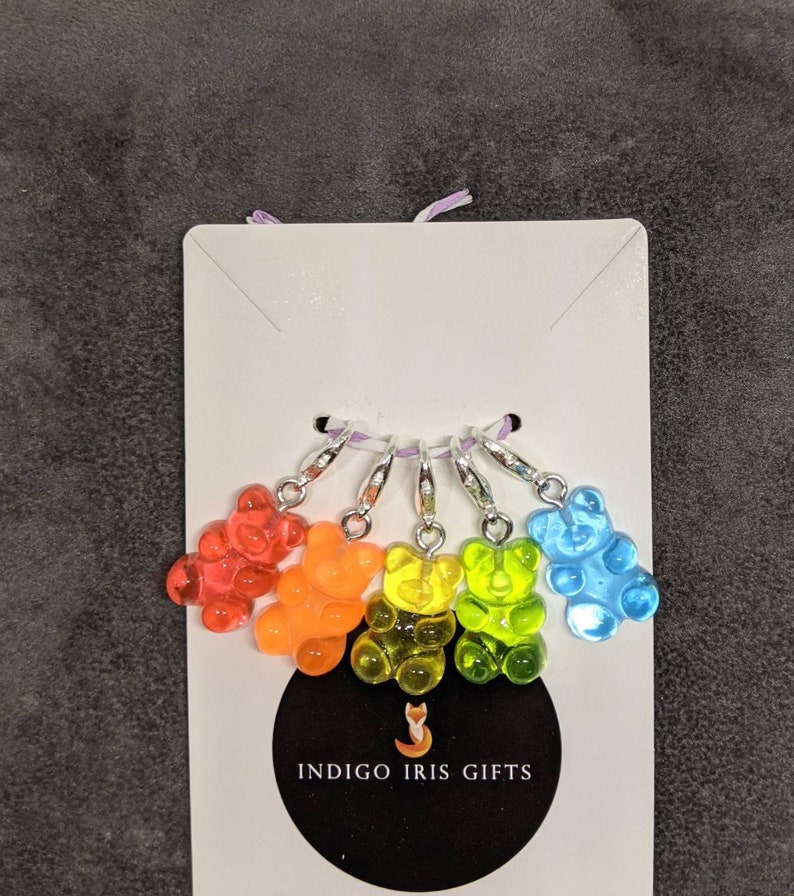 Puede incluir: Conjunto de seis marcadores de punto de osito gominola arco&iacute;ris con anillos plateados. Los ositos gominola son rojo, naranja, amarillo, verde, azul y morado. Los marcadores de punto est&aacute;n etiquetados con "INDIGO IRIS GIFTS".