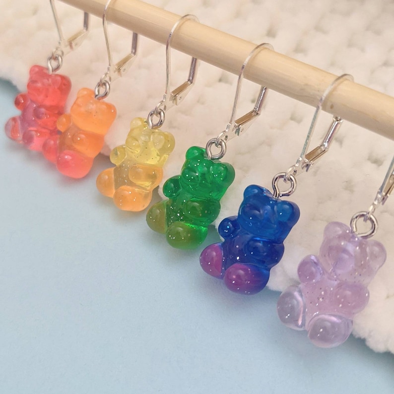 Puede incluir: Pendientes de osito de gominola arco&iacute;ris. Los pendientes est&aacute;n hechos de pl&aacute;stico transparente y tienen forma de osito de gominola. Los ositos de gominola son de los colores del arco&iacute;ris: rojo, naranja, amarillo, verde, azul y morado.