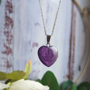 May include: A silver chain necklace with a purple heart-shaped amethyst pendant.