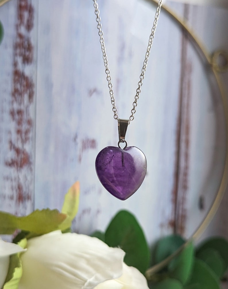 May include: A silver chain necklace with a purple heart-shaped amethyst pendant.