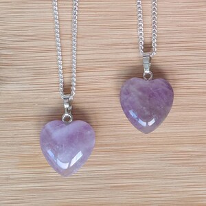 May include: Two silver chains with amethyst heart pendants. The hearts are a light purple color and have a smooth, polished finish.