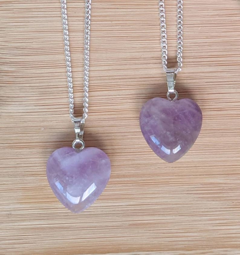 May include: Two silver chains with amethyst heart pendants. The hearts are a light purple color and have a smooth, polished finish.