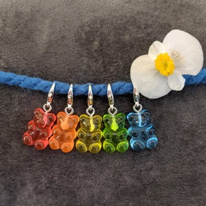 Puede incluir: Cinco marcadores de punto en forma de osito de goma en un arco&iacute;ris de colores: rojo, naranja, amarillo, verde y azul. Los marcadores est&aacute;n unidos a un hilo azul con anillos plateados.