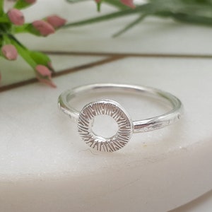 Könnte beinhalten: Ein silberner Ring mit einem strukturierten, runden Design. Der Ring ist schlicht und elegant.