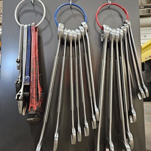 May include: A set of spanners hanging on magnetic hooks. The spanners are organised by size and are all silver in colour. The hooks are attached to a grey metal surface.