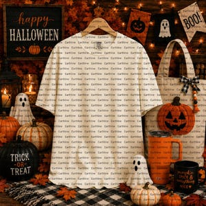 Könnte beinhalten: Ein cremefarbenes Kurzarm-T-Shirt mit einem sich wiederholenden Muster des Wortes Earthline in schwarzer Schrift auf dem gesamten Stoff, präsentiert auf einem Holzkleiderbügel vor einem festlichen Halloween-Hintergrund.