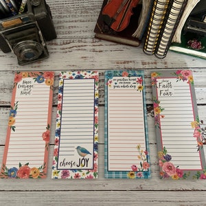 May include: Four floral patterned notepad sets with inspirational quotes. The quotes are "Have Courage and Be Kind", "Choose Joy", "One Positive Thought Can Change Your Whole Day", and "Choose Faith Not Fear".