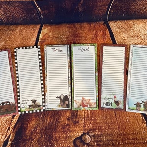 May include: Six magnetic shopping list pads with farm-themed designs. The pads have a white background with black lines and feature different farm animals, including a cow, pigs, a rooster, and sheep. The text on the pads includes "Farm Sweet Farm", "Go Local", and "Life is Better on the Farm".