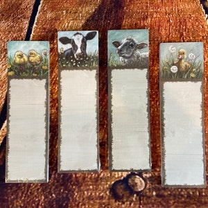 May include: Four farmhouse-style memo pads with different animal illustrations. The top pad features a cow, the second pad features a lamb, the third pad features a chick, and the fourth pad features a duckling.