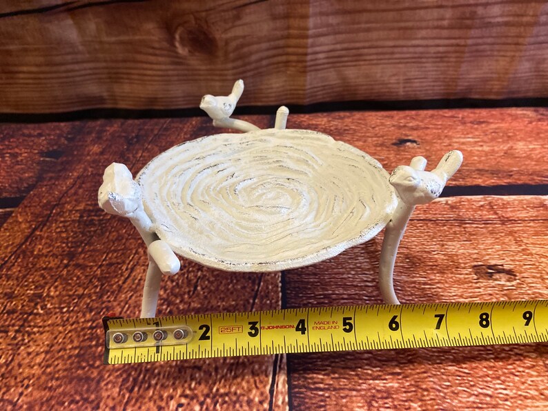 May include: A white, bird-themed decorative tray. The tray is oval-shaped, with a textured surface and supported by three bird-shaped legs. The tray is approximately 6 inches long.