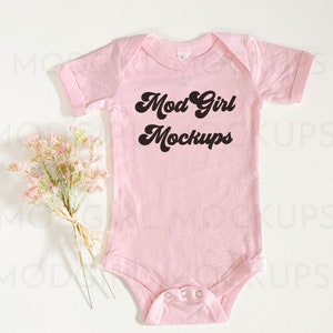 May include: Pink baby onesie with the text "Mod Girl Mockups" in black.