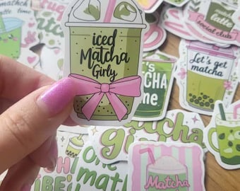 May include: A collection of matcha-themed stickers, with a focus on iced matcha drinks. One sticker is held up, featuring a green iced matcha drink with a pink bow and the text "iced Matcha Girly". Other stickers include phrases like "Matcha Latte" and "Let's get matcha".