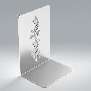 May include: A silver-colored metal bookend with an L-shaped design. The vertical panel features a laser-cut, intricate floral or vine-like pattern running vertically down the center. The surface has a smooth, reflective, and polished metallic finish.