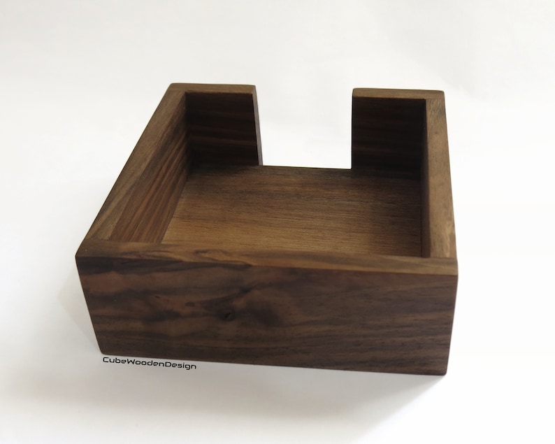 K&ouml;nnte beinhalten: Ein dunkelbrauner, quadratischer Holz-Tischtuchhalter mit offener Oberseite. Der Halter ist aus massivem Holz gefertigt und hat eine nat&uuml;rliche Oberfl&auml;che. Der Text "CubeWoodenDesign" ist auf der Unterseite des Halters sichtbar.