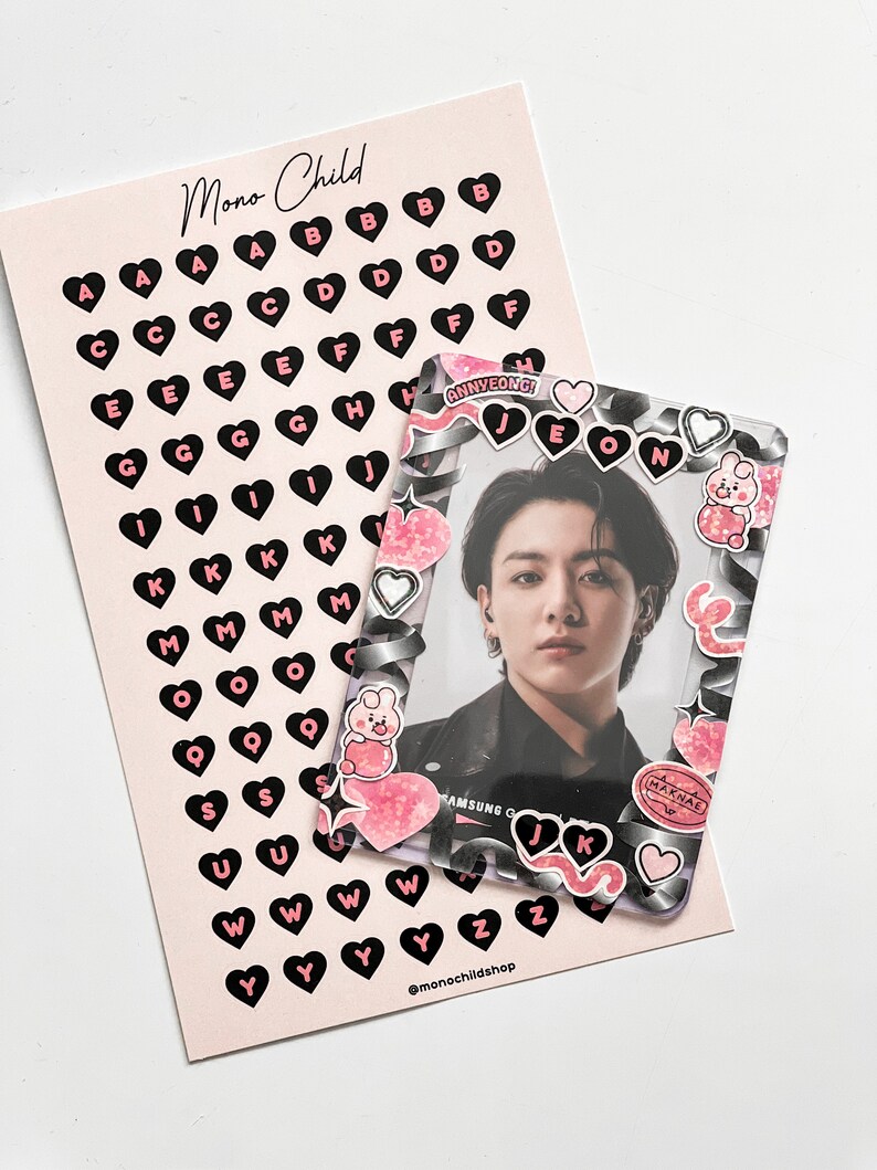 May include: A pink card with black heart-shaped letter stickers and a clear photo frame. The frame has decorative stickers and a photo of a person. The card has the text "Mono Child" and "@monochildshop".