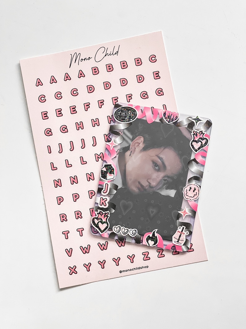 May include: A pink sheet of alphabet stickers and a photo card. The stickers are pink with black outlines. The photo card has a decorative frame with pink and silver accents and various stickers. The text "Mono Child" is visible.