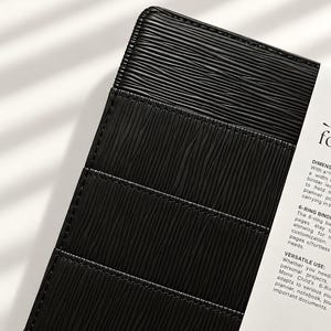 Puede incluir: Una carpeta de 6 anillas negra con un patr&oacute;n de l&iacute;neas horizontales texturizadas en la cubierta. Un inserto de papel blanco est&aacute; unido al lateral, con texto impreso que incluye las palabras DIMENSIONS, 6-RING BINDER y VERSATILE USE, describiendo el producto.